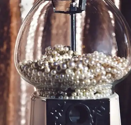 This image of pearls in a glass gumball machine depicts.