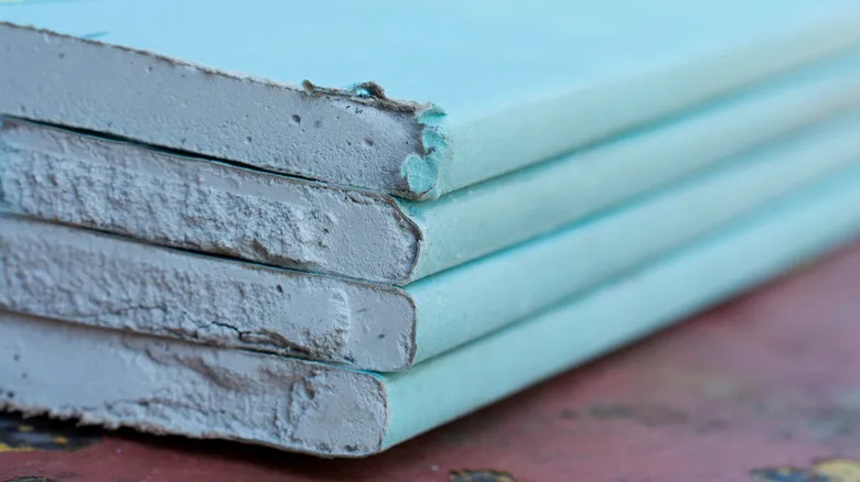 Plaques de cloison sèche avec un revêtement vert, conçues pour résister à l'humidité dans les espaces comme les salles de bains et les cuisines.