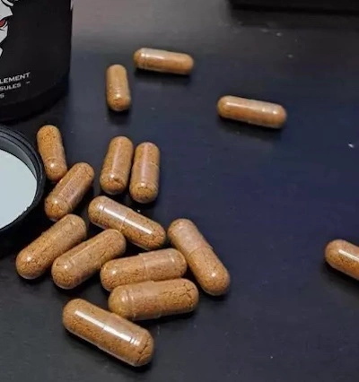 Several Aphro-D testosterone booster pills scattered on a table, showcasing their size, color and shape